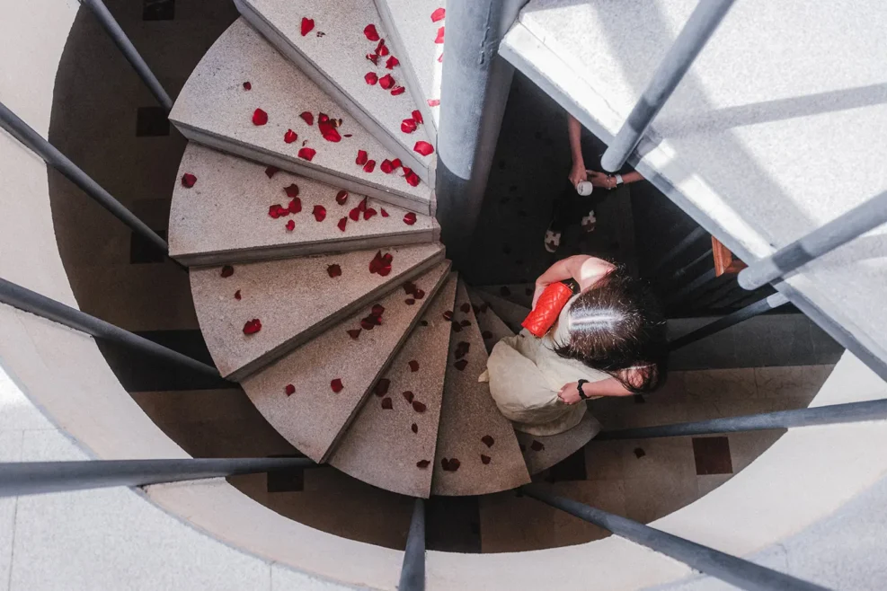 Mujer subiendo una escalera decorada con pétalos antes de una pedida de mano con ceremonia personalizada